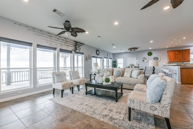 living area with ceiling fan, plenty of natural light, and visible vents