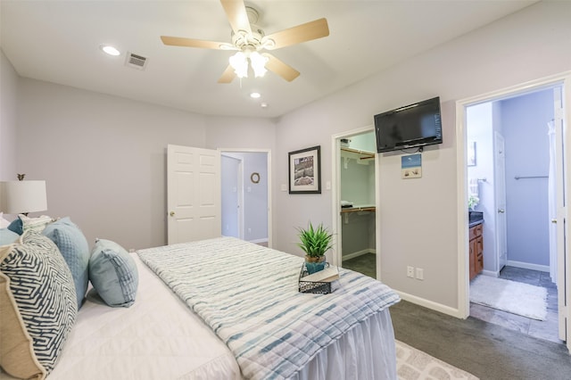 bedroom with a ceiling fan, a walk in closet, visible vents, carpet, and baseboards