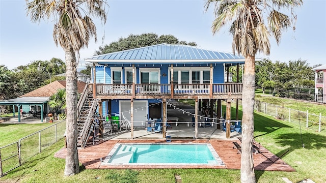 rear view of house with a fenced backyard, stairway, metal roof, a patio area, and a lawn