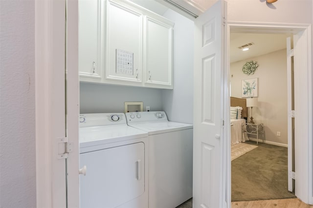 clothes washing area with cabinet space, independent washer and dryer, light carpet, and visible vents