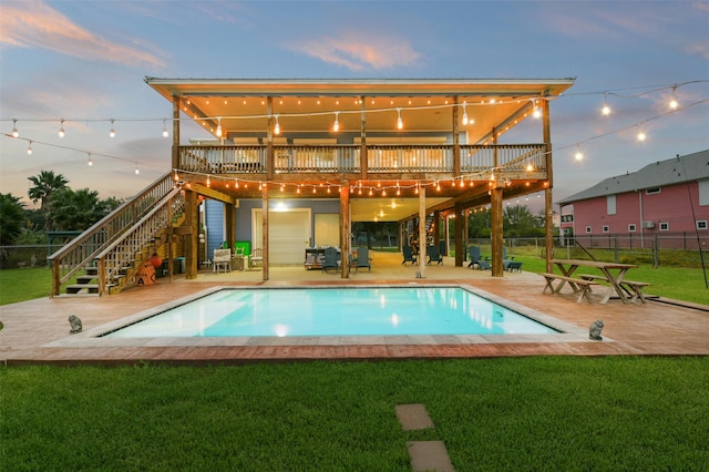 back of house at dusk with a wooden deck, stairway, a patio area, a yard, and fence