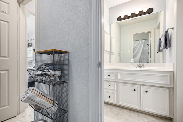 full bath with tile patterned floors, a textured wall, and vanity