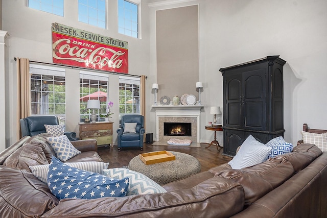 living room featuring a fireplace with flush hearth, wood finished floors, baseboards, and a high ceiling