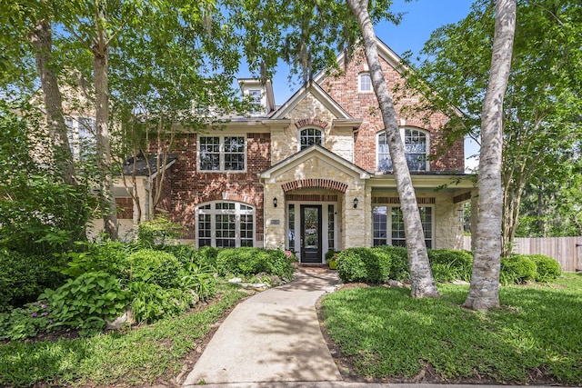 view of front of house with brick siding, stone siding, and fence