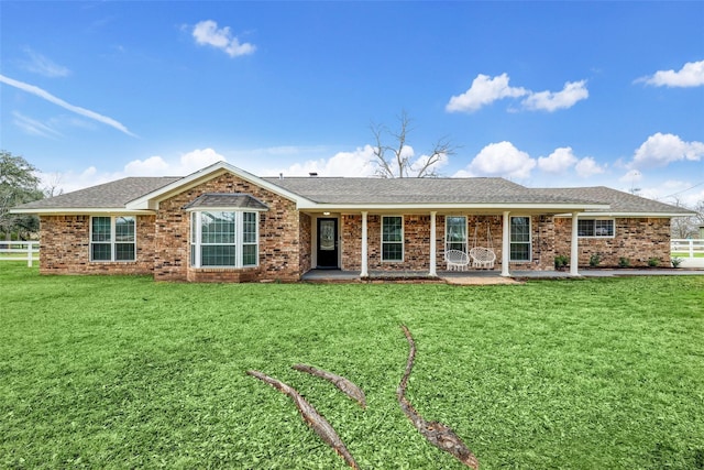 ranch-style house featuring fence, a front lawn, and roof with shingles