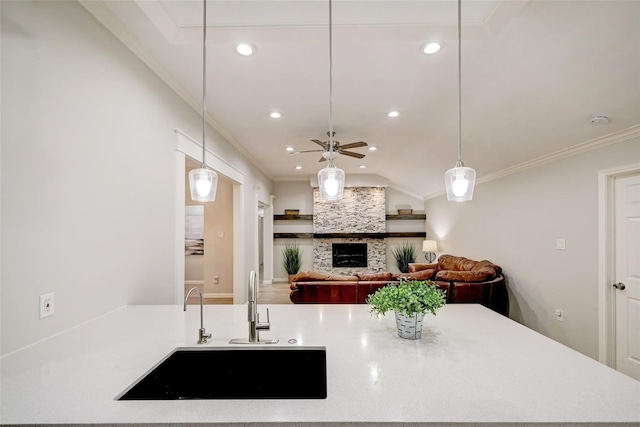kitchen featuring a sink, a fireplace, ceiling fan, decorative light fixtures, and ornamental molding