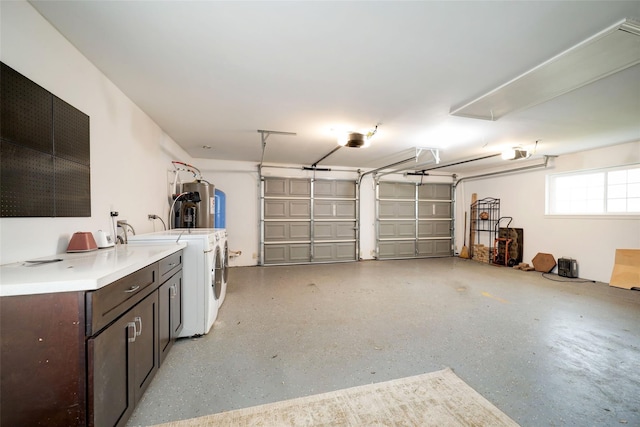 garage with water heater, washing machine and clothes dryer, and a garage door opener