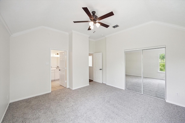 unfurnished bedroom featuring visible vents, light colored carpet, vaulted ceiling, baseboards, and a closet