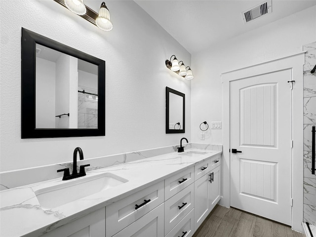 full bath with double vanity, wood finished floors, visible vents, and a sink