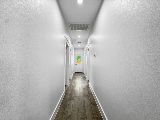 hall featuring dark wood-type flooring, visible vents, recessed lighting, and baseboards