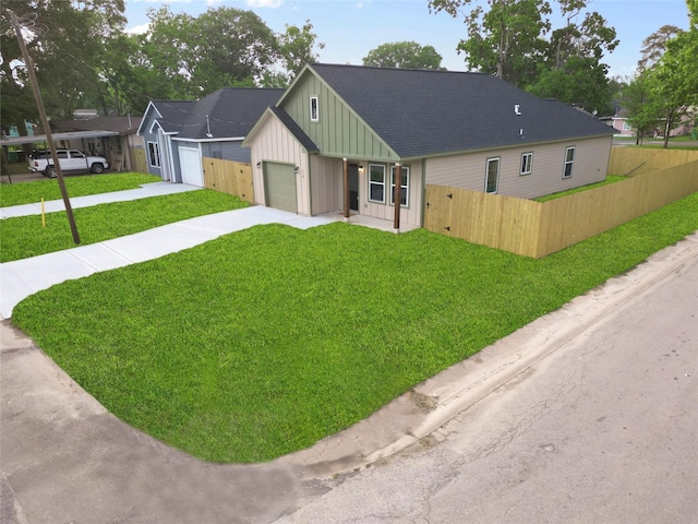 view of front of house with board and batten siding, fence, a garage, driveway, and a front lawn