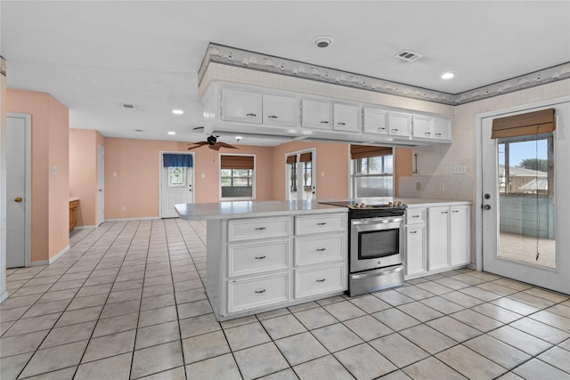 1114 Helen Dowdy Prt, Bolivar, TX 77650 - kitchen with stainless steel range with electric cooktop, a peninsula, light countertops, light tile patterned floors, and white cabinets
