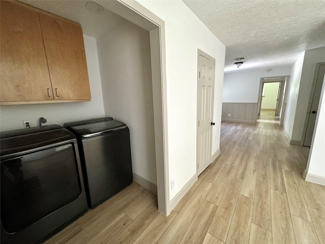 1402 Firwood Cir, Pasadena, TX 77502 - laundry area featuring light wood-style flooring, washer and clothes dryer, a textured ceiling, wainscoting, and baseboards