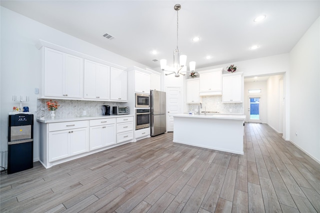 10554 Cecilia Star Ln, Richmond, TX 77406 - kitchen with appliances with stainless steel finishes, a chandelier, decorative backsplash, light wood-style flooring, and light countertops