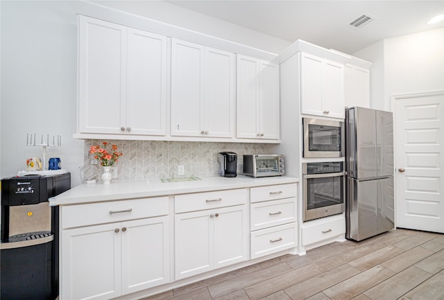 10554 Cecilia Star Ln, Richmond, TX 77406 - kitchen featuring stainless steel appliances, light wood-type flooring, light countertops, white cabinets, and tasteful backsplash