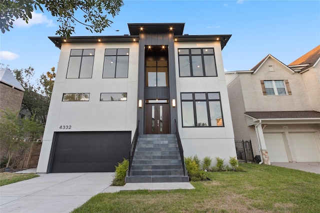 modern home with a front lawn, driveway, a garage, and stucco siding