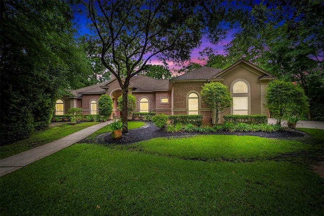 view of front of property featuring roof with shingles, brick siding, and a front lawn