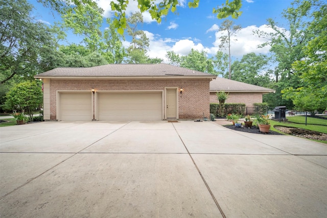 view of front facade featuring a garage, brick siding, roof with shingles, concrete driveway, and fence