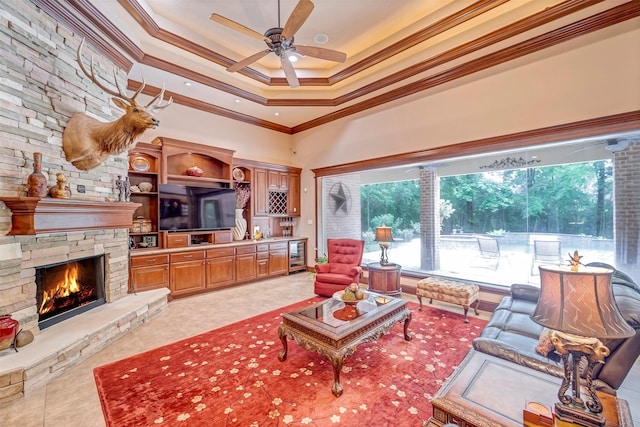 living room featuring beverage cooler, ornamental molding, a fireplace, a ceiling fan, and a high ceiling