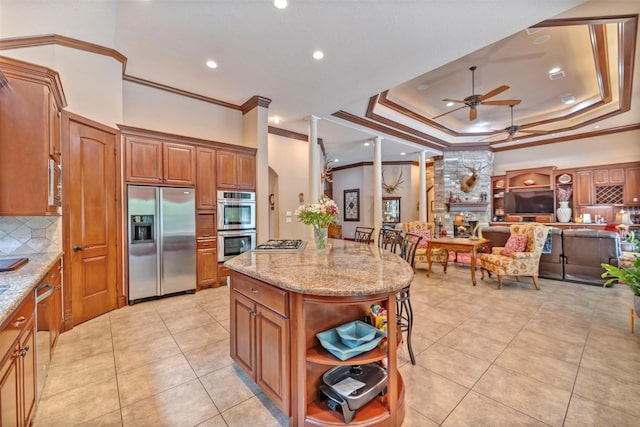 kitchen with light stone countertops, appliances with stainless steel finishes, ornamental molding, backsplash, and a ceiling fan