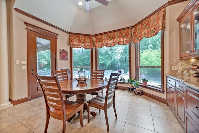 dining area featuring light tile patterned floors, a ceiling fan, lofted ceiling, and baseboards