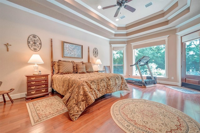 bedroom with a raised ceiling, light wood-type flooring, crown molding, access to exterior, and visible vents