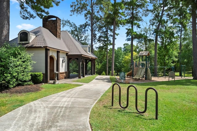 view of home's community featuring driveway, a yard, and playground community