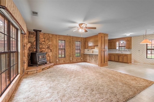 350 Shoreline Dr, Huntsville, TX 77320 - unfurnished living room with a wood stove, a ceiling fan, visible vents, baseboards, and wallpapered walls
