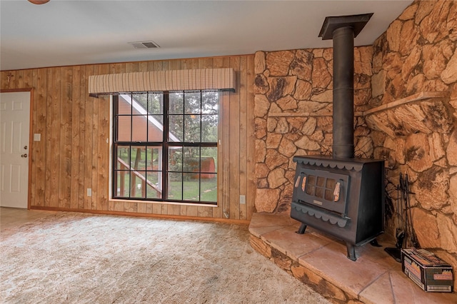 350 Shoreline Dr, Huntsville, TX 77320 - unfurnished living room featuring a wood stove, visible vents, wood walls, baseboards, and carpet floors
