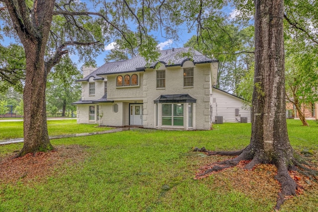 561 Brandon Rd, Conroe, TX 77302 - traditional-style home with a chimney, brick siding, a front yard, and central air condition unit