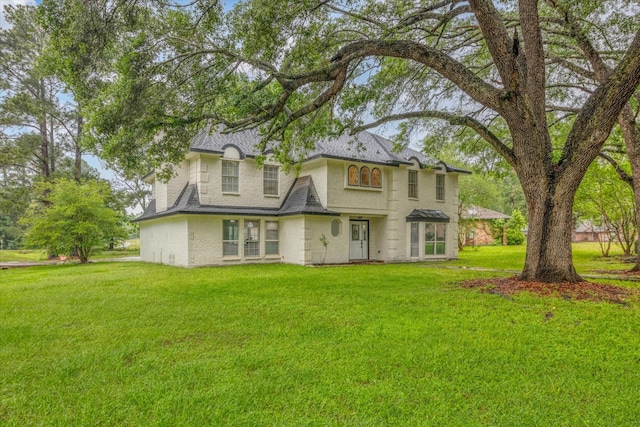 561 Brandon Rd, Conroe, TX 77302 - rear view of house featuring roof with shingles, a yard, and brick siding