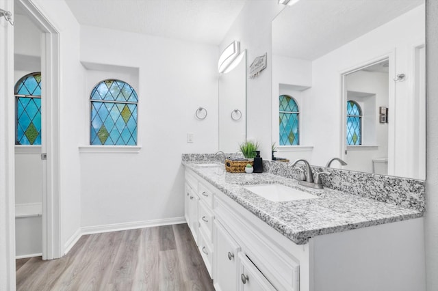 561 Brandon Rd, Conroe, TX 77302 - bathroom featuring double vanity, a sink, wood finished floors, and baseboards