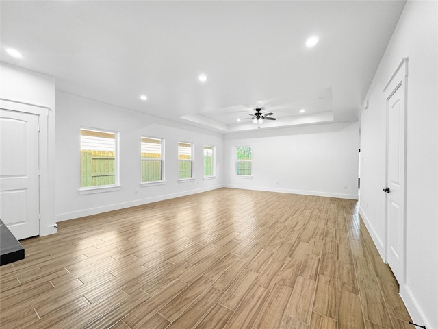 unfurnished living room featuring recessed lighting, a raised ceiling, a ceiling fan, and light wood finished floors