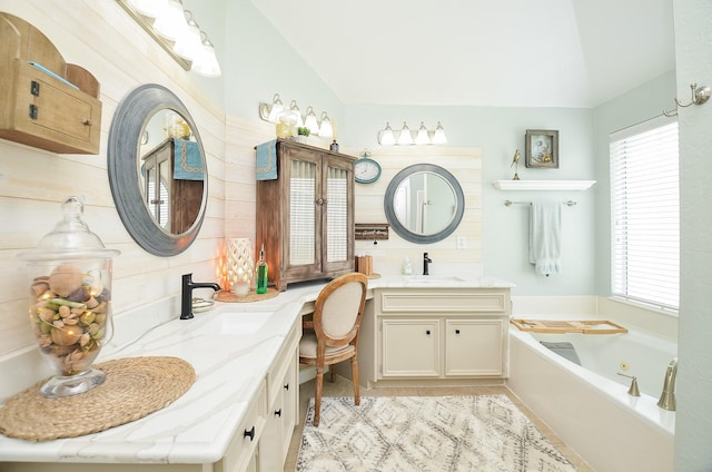 full bath with two vanities, a whirlpool tub, lofted ceiling, and a sink