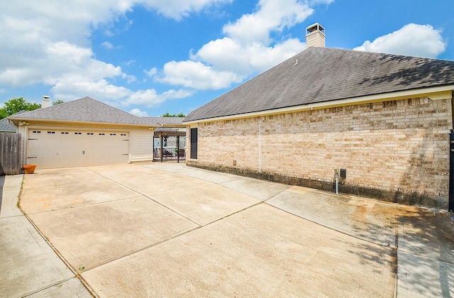 view of property exterior with driveway, a garage, fence, and a chimney