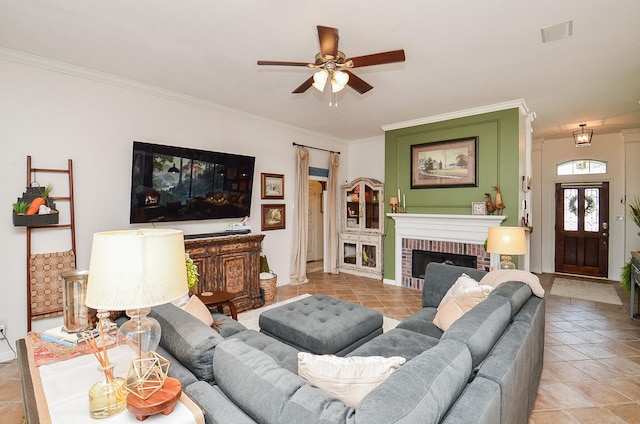 tiled living area with ornamental molding, ceiling fan, a brick fireplace, and baseboards