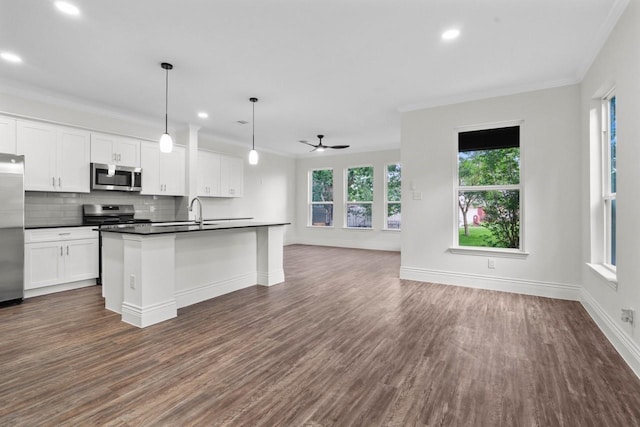 12975 Corona Ct, Willis, TX 77318 - kitchen featuring dark wood-type flooring, open floor plan, dark countertops, and stainless steel appliances
