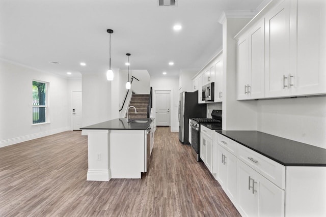 12975 Corona Ct, Willis, TX 77318 - kitchen featuring dark countertops, appliances with stainless steel finishes, crown molding, and wood finished floors