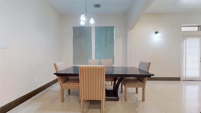 dining room with light tile patterned floors, visible vents, arched walkways, an inviting chandelier, and baseboards