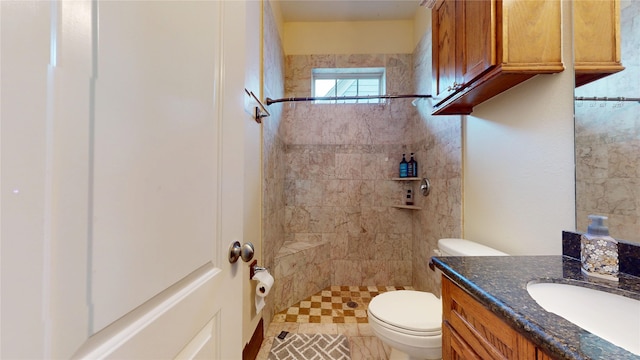 full bath featuring toilet, tiled shower, and vanity