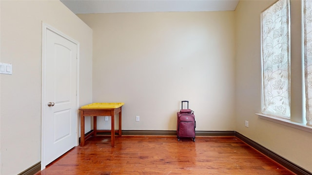 spare room with baseboards and wood finished floors