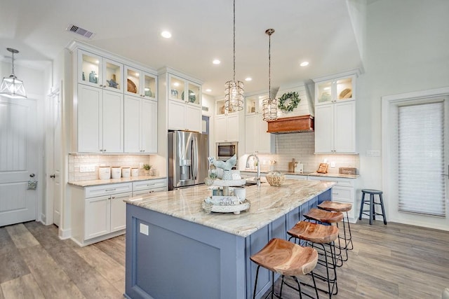 4110 Defender Ln, Galveston, TX 77554 - kitchen with tasteful backsplash, light wood-style flooring, a breakfast bar area, stainless steel appliances, and custom range hood