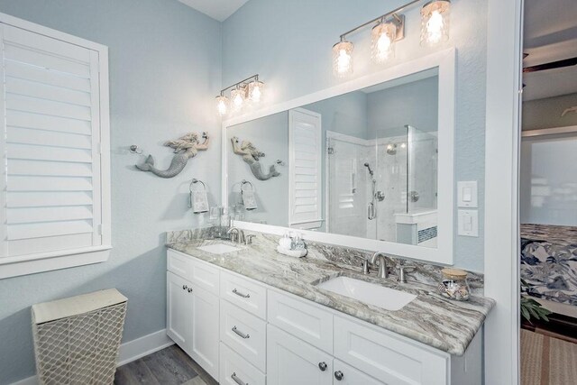 4110 Defender Ln, Galveston, TX 77554 - bathroom featuring a stall shower, double vanity, a sink, and wood finished floors
