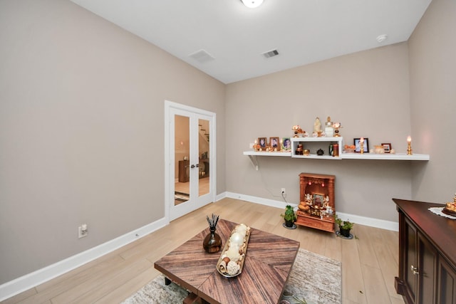 sitting room with baseboards, visible vents, french doors, and light wood finished floors