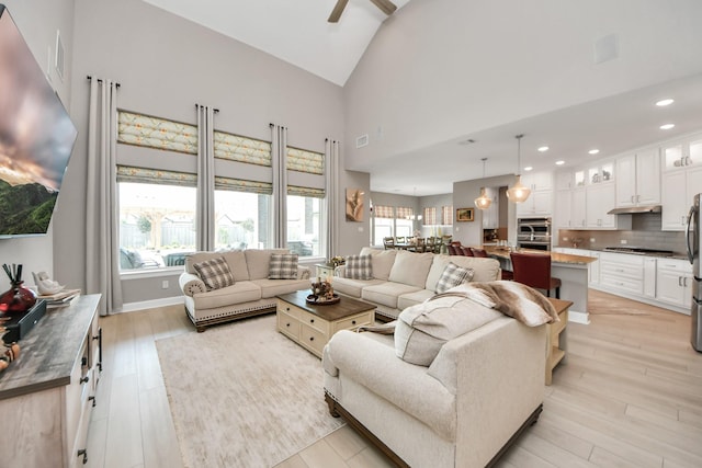 living room featuring a ceiling fan, recessed lighting, a healthy amount of sunlight, and light wood-style floors