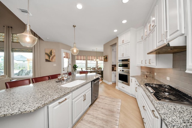 kitchen with stainless steel appliances, visible vents, white cabinetry, and a sink
