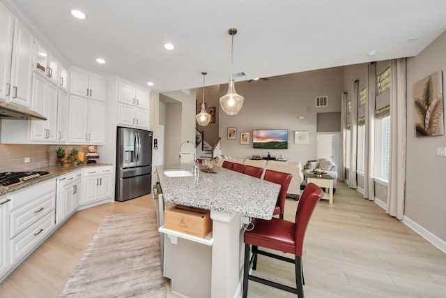 kitchen featuring decorative backsplash, visible vents, appliances with stainless steel finishes, a sink, and light wood-style flooring