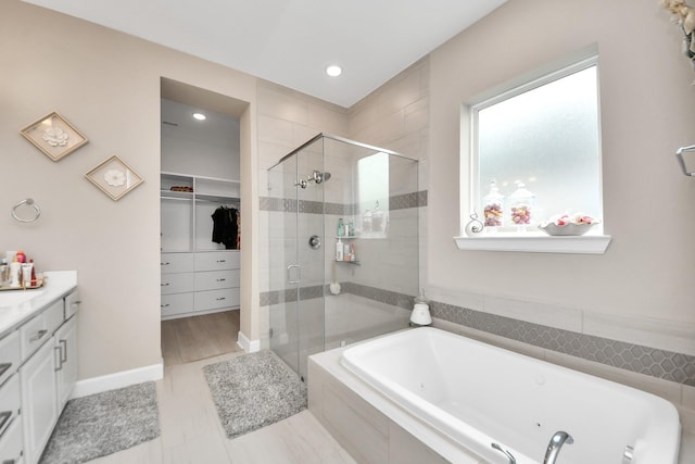 full bathroom with vanity, recessed lighting, a tub with jets, a spacious closet, and a stall shower