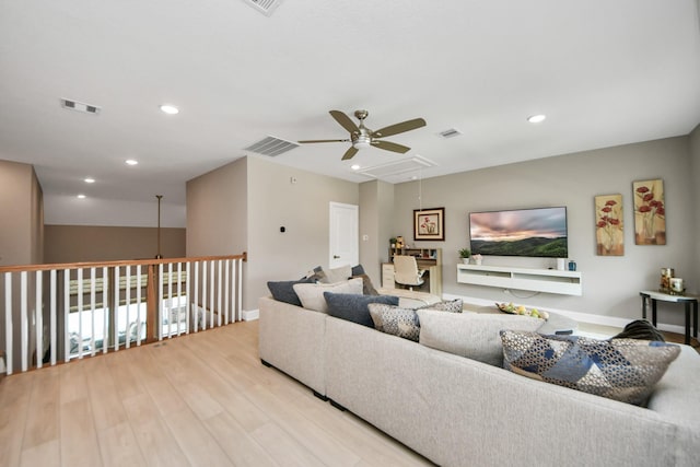 living area featuring visible vents, attic access, light wood-style floors, and a ceiling fan