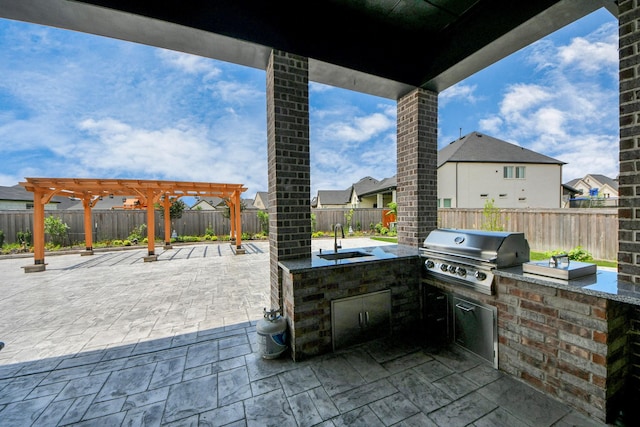 view of patio / terrace featuring grilling area, exterior kitchen, a sink, a fenced backyard, and a pergola